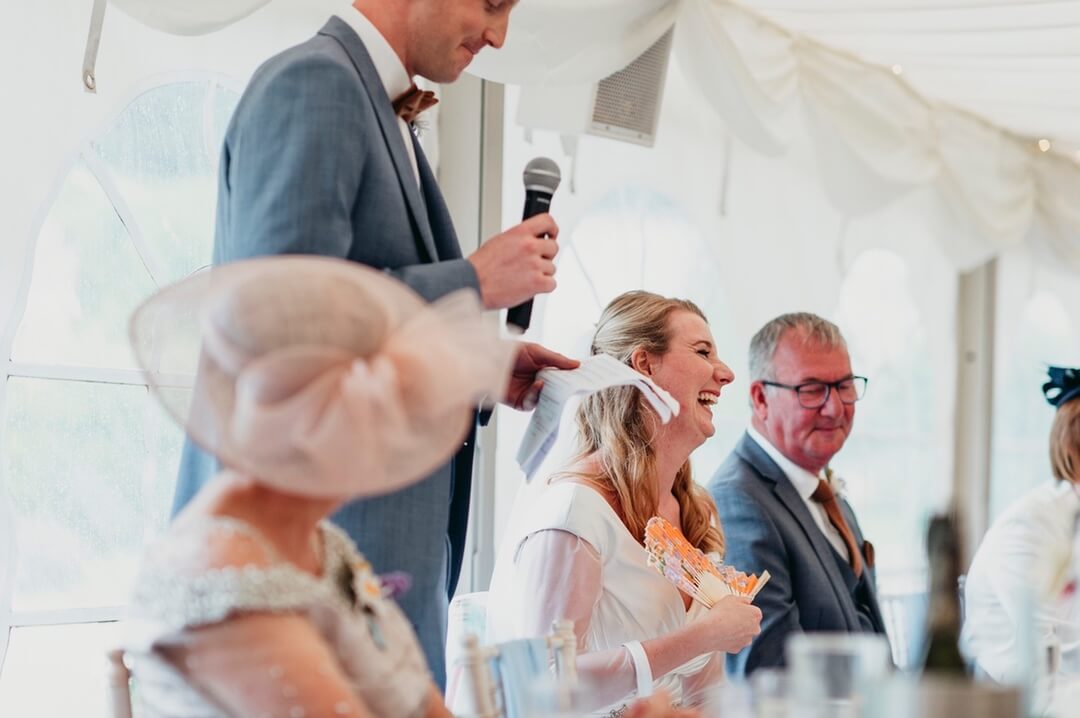 Bride laughing during Groomsman's speech