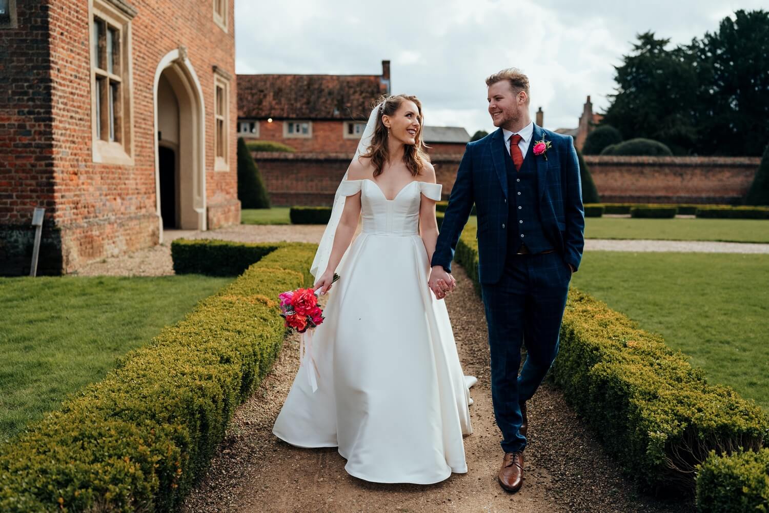 Bride and groom walking through grounds of Doddington Hall