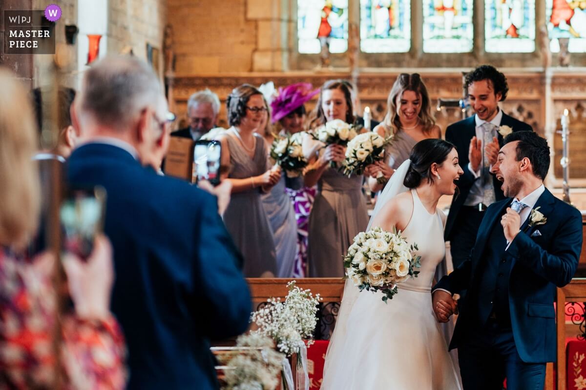 Bride and groom coming down aisle before heading to Hodsock Priory reception