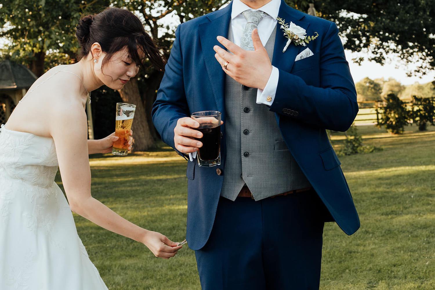 Bride placing a peg on the grooms suit outside Pheasantry Brewery
